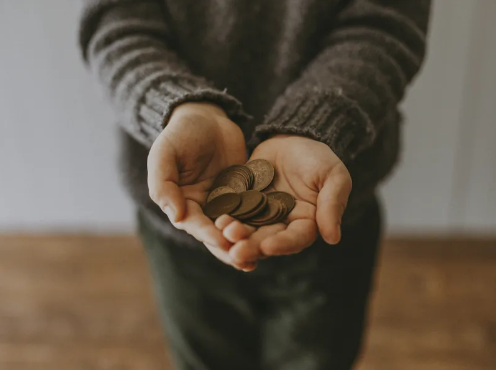 Hands holding coins to represent poverty and essentials support